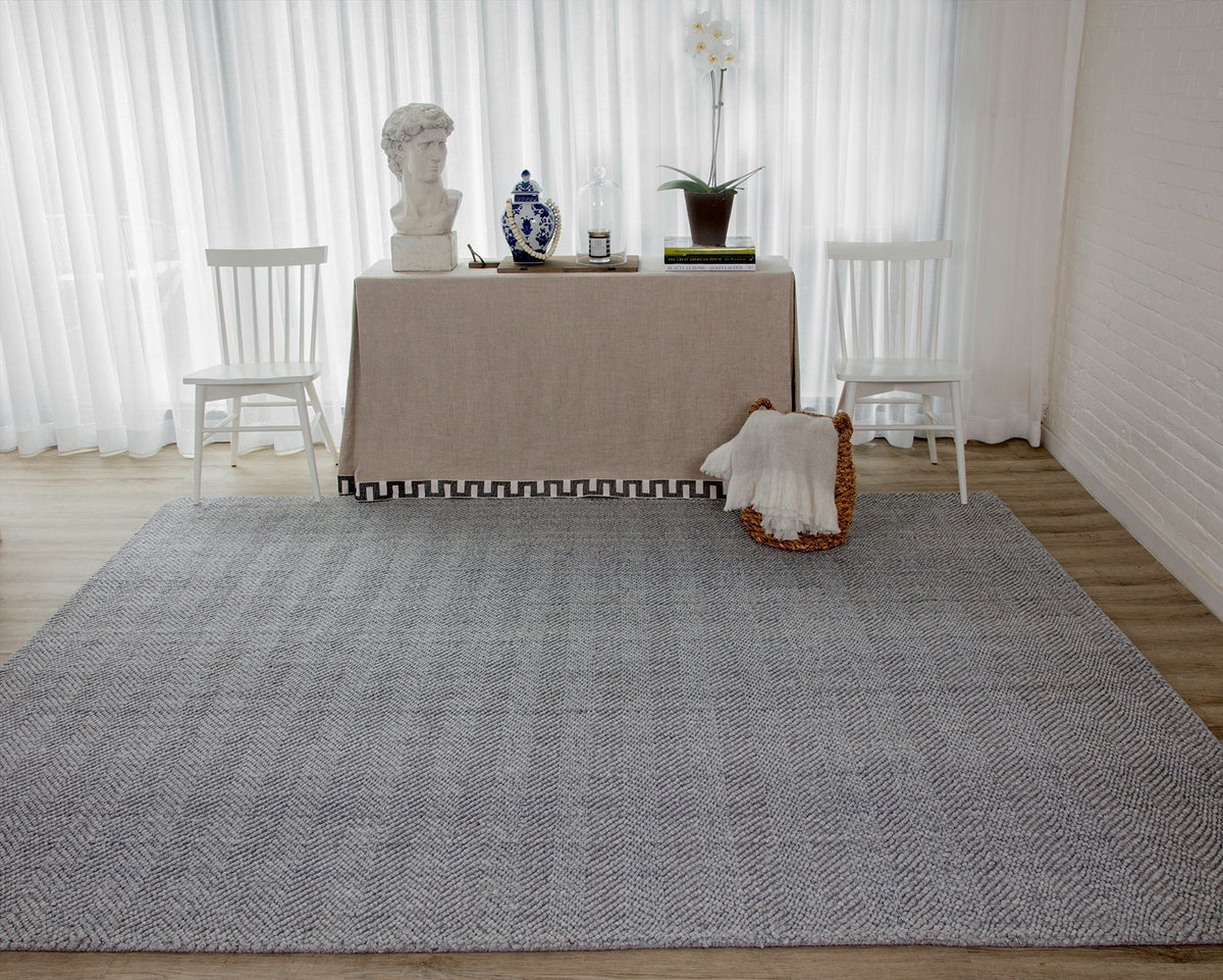 Erin Gates by Momeni Gray Ledgebrook rug with delicate herringbone pattern laid on wood floor beneath a table styled with decor and white chairs.