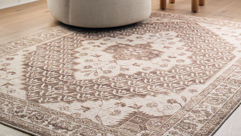 Nabela Noor Athiyo area rug featuring a traditional beige and brown floral medallion pattern on light wood flooring.