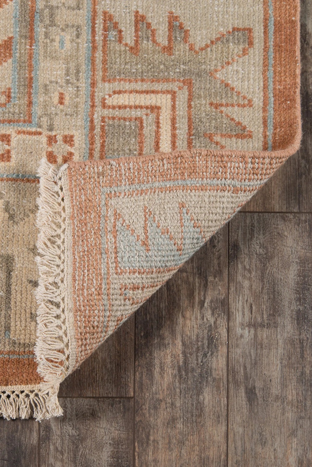 Erin Gates by Momeni Hand-knotted Concord CRD-1 Walden area rug in rust with tribal motifs and fringed corner resting on dark wood flooring.