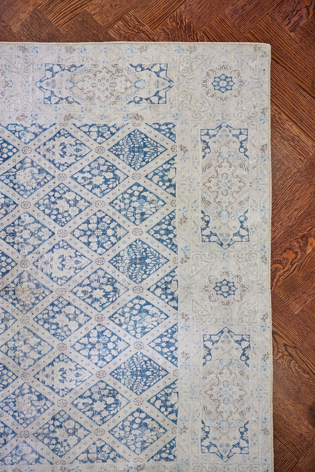 Erin Gates by Momeni Dorset DOR-3 blue area rug featuring a vintage diamond lattice pattern and distressed floral motifs on a cream background over hardwood.