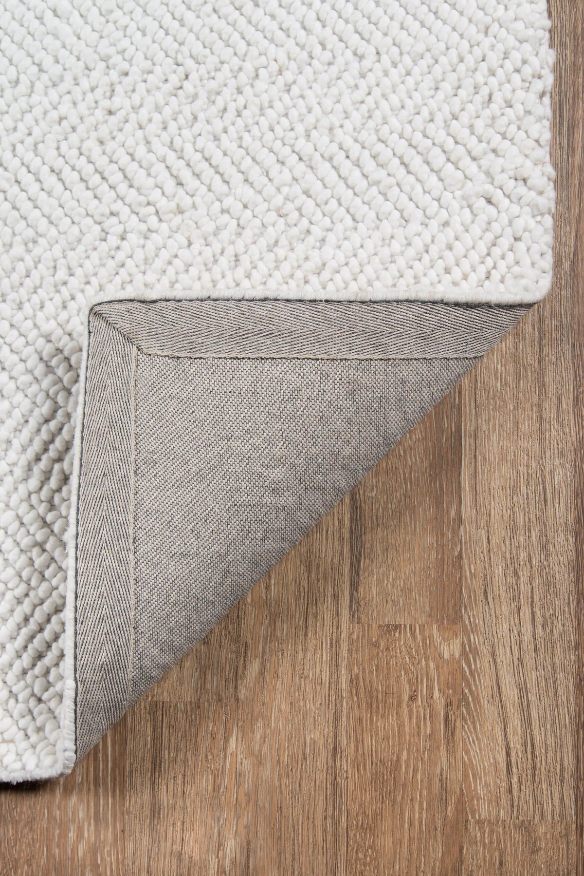 Erin Gates by Momeni Ledgebrook LED-1 Ivory area rug corner lifted to display textured loop pile and grey canvas backing on wood flooring.