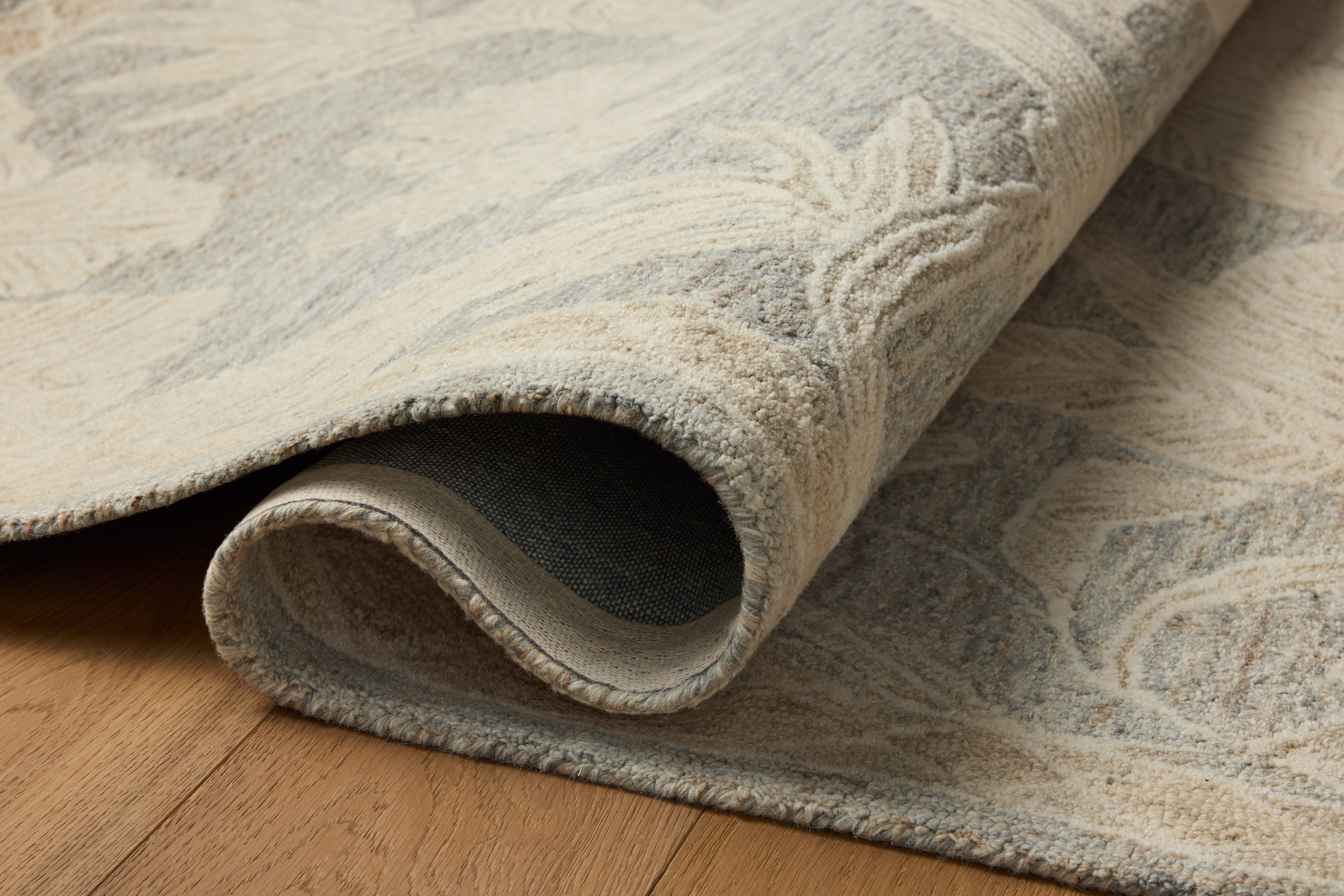 A hand-tufted wool area rug with floral flair in calming blue and warm natural tones, the Lenore LNO-01 Blue / Natural Area Rug anchors any room