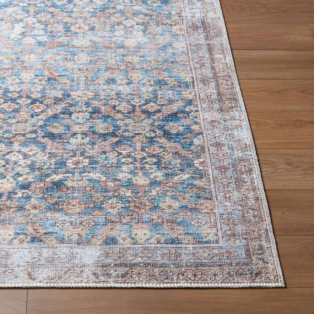 Amelia Slate Blue Area Rug with a distressed traditional pattern on a wood floor.