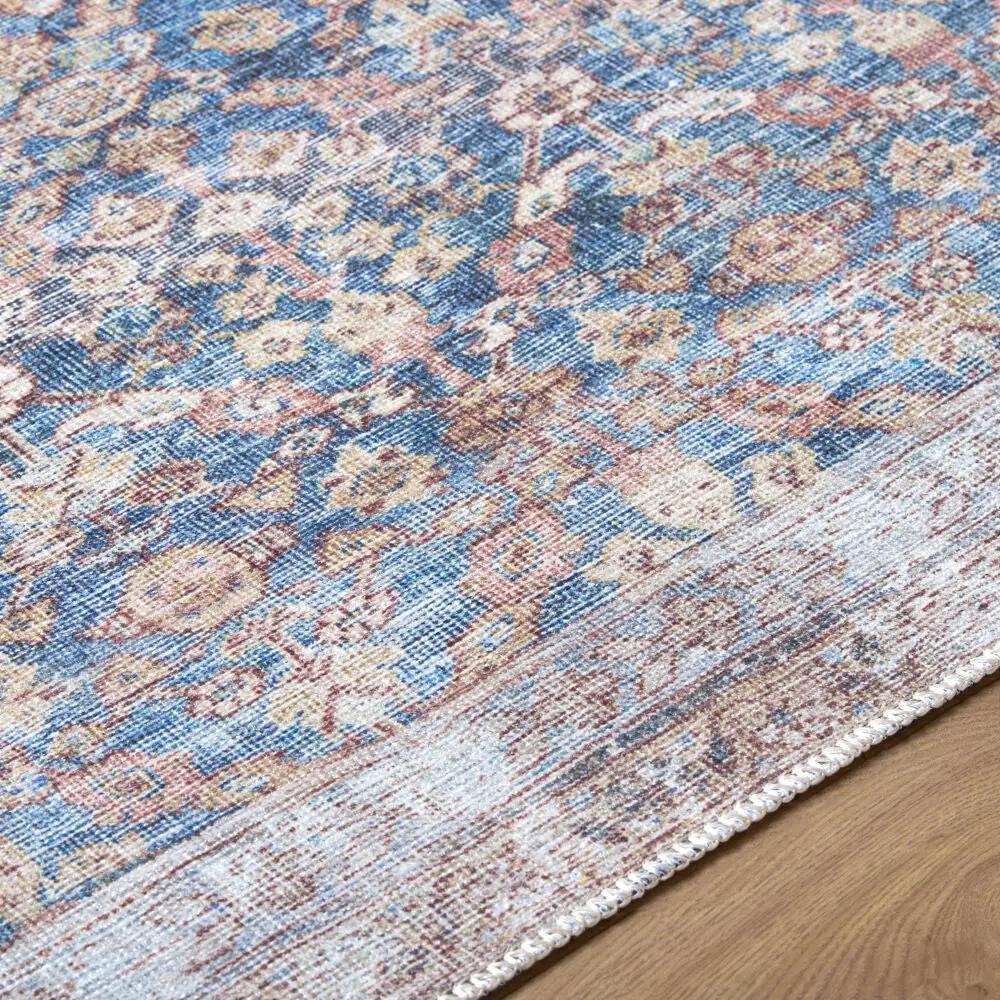 Close-up of the Amelia Slate Blue Area Rug showing its distressed floral pattern and low pile.