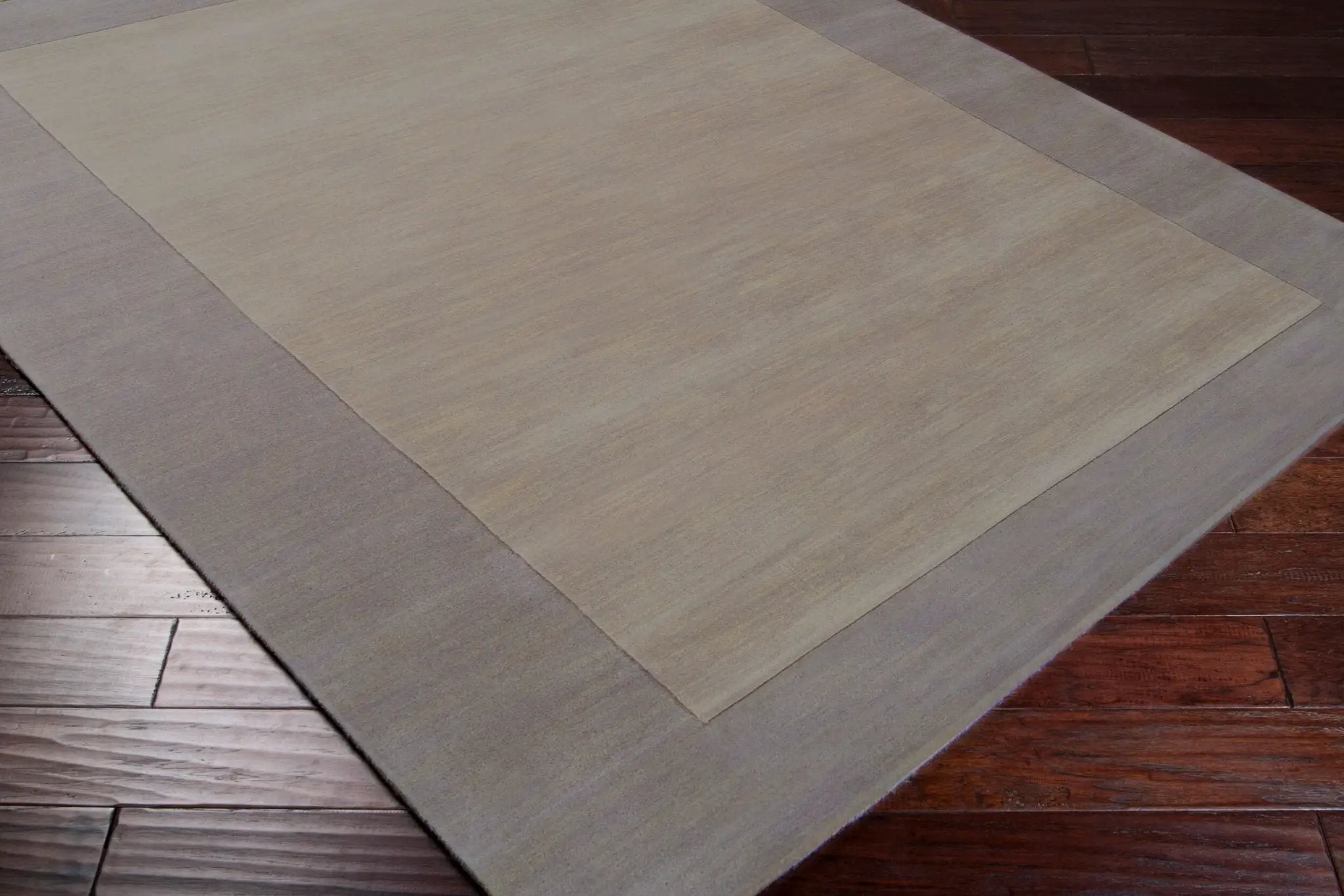 Livabliss Mystique M-312 charcoal area rug with contrasting border and textured high/low pile, laid over dark hardwood flooring.