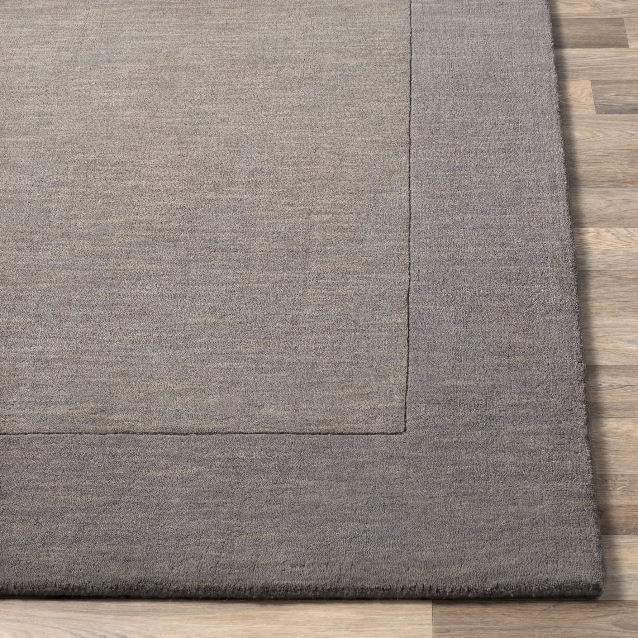 Livabliss Mystique M-312 charcoal area rug with high-low pile texture and defined border on wood flooring.