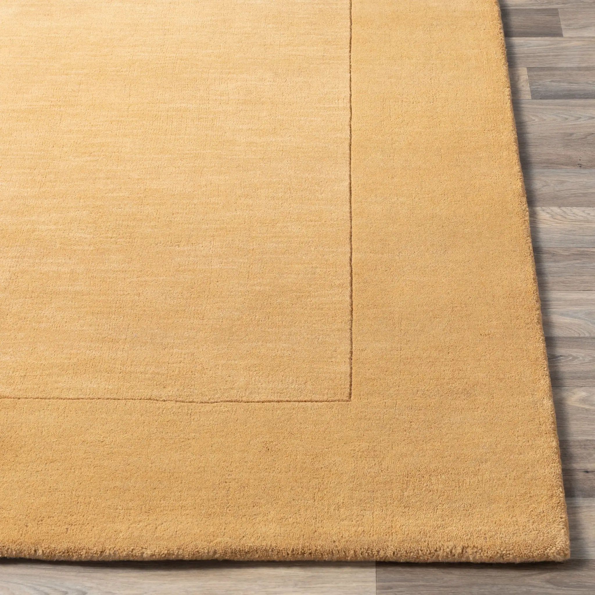 Livabliss Mystique M-345 Camel color area rug with textured surface and tonal border design, laid over light wood flooring for a warm, contemporary look.
