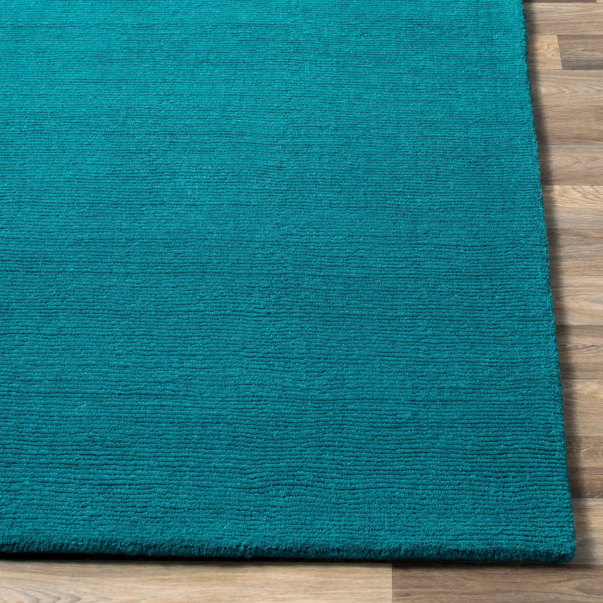 Livabliss Mystique M-5330 Deep teal hand-loomed wool area rug with contemporary high-low texture resting on light wood flooring.