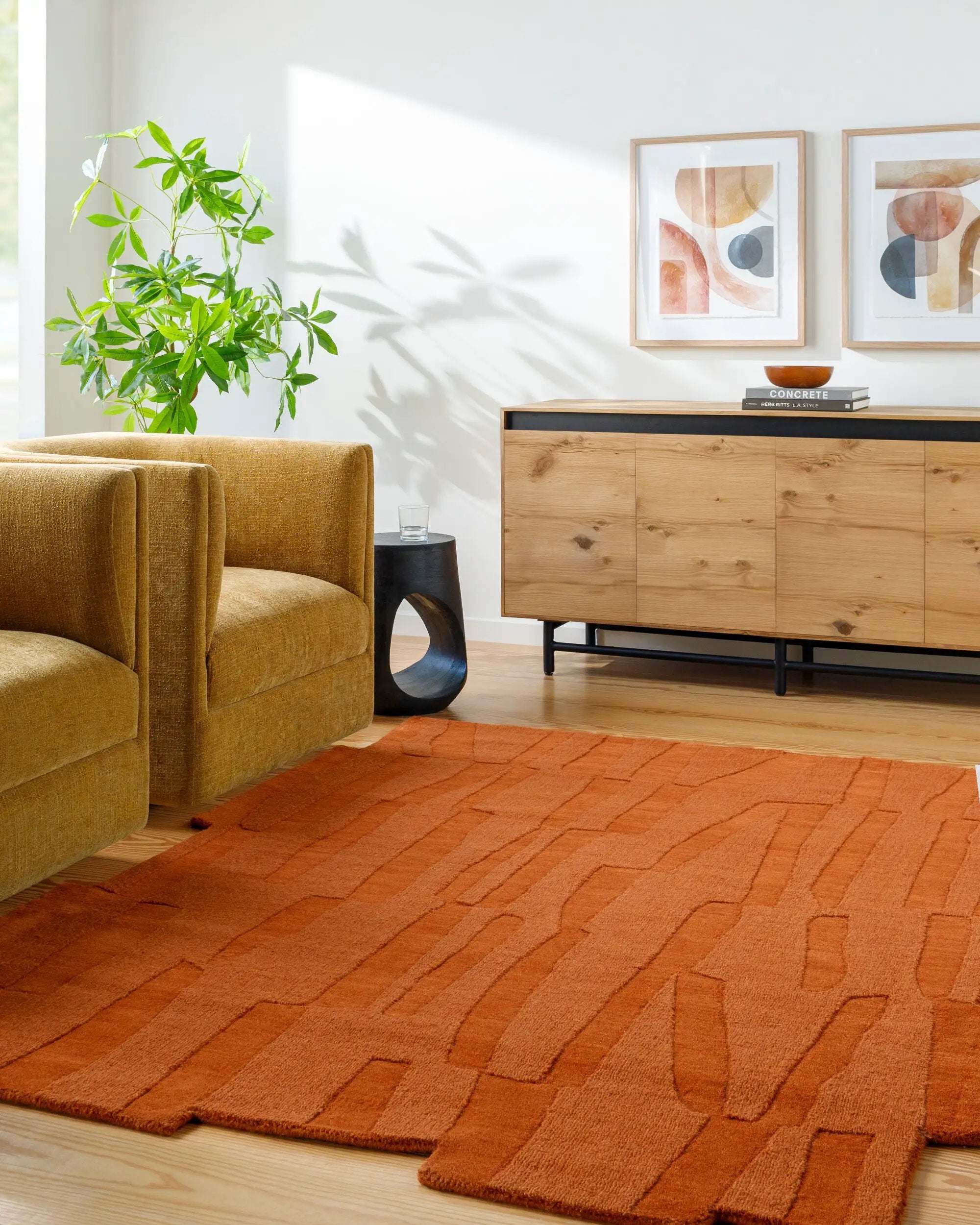 Livabliss Mystique M-5488 Burnt sienna wool area rug with textured geometric pattern in a modern living room featuring a mustard chair and wood console.