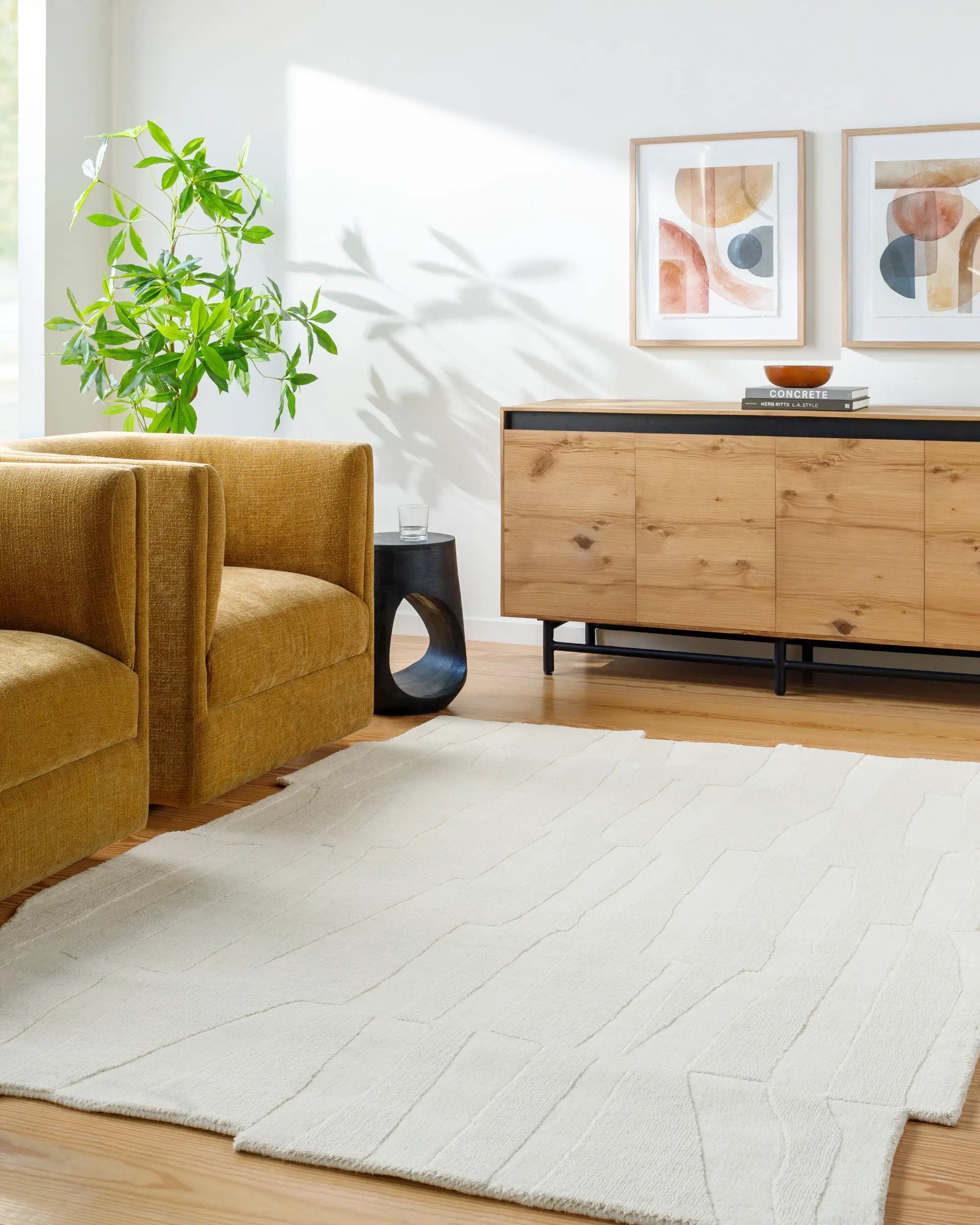 Livabliss Mystique M-5489 Ivory hand-loomed wool area rug with textured geometric pattern anchoring a modern living room with mustard chair and wooden sideboard.