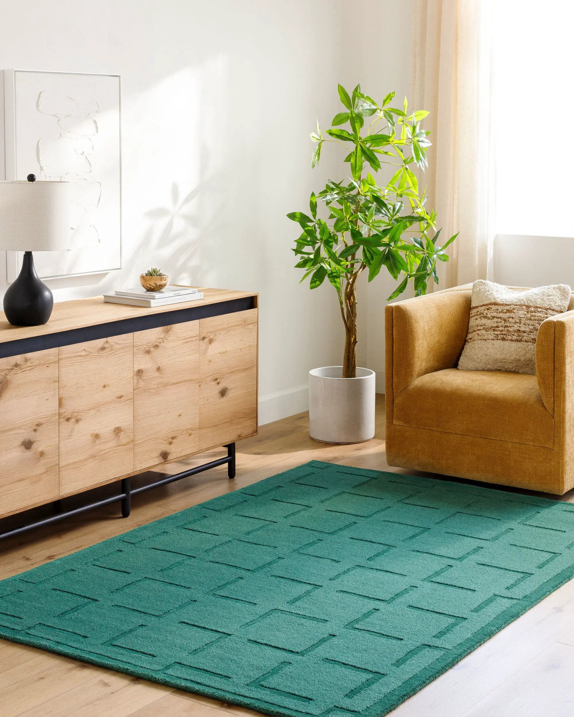 Livabliss Hand Loomed Mystique M-5490 Emerald Green area rug with textured geometric pattern in a modern living room featuring a wooden sideboard and mustard armchair.