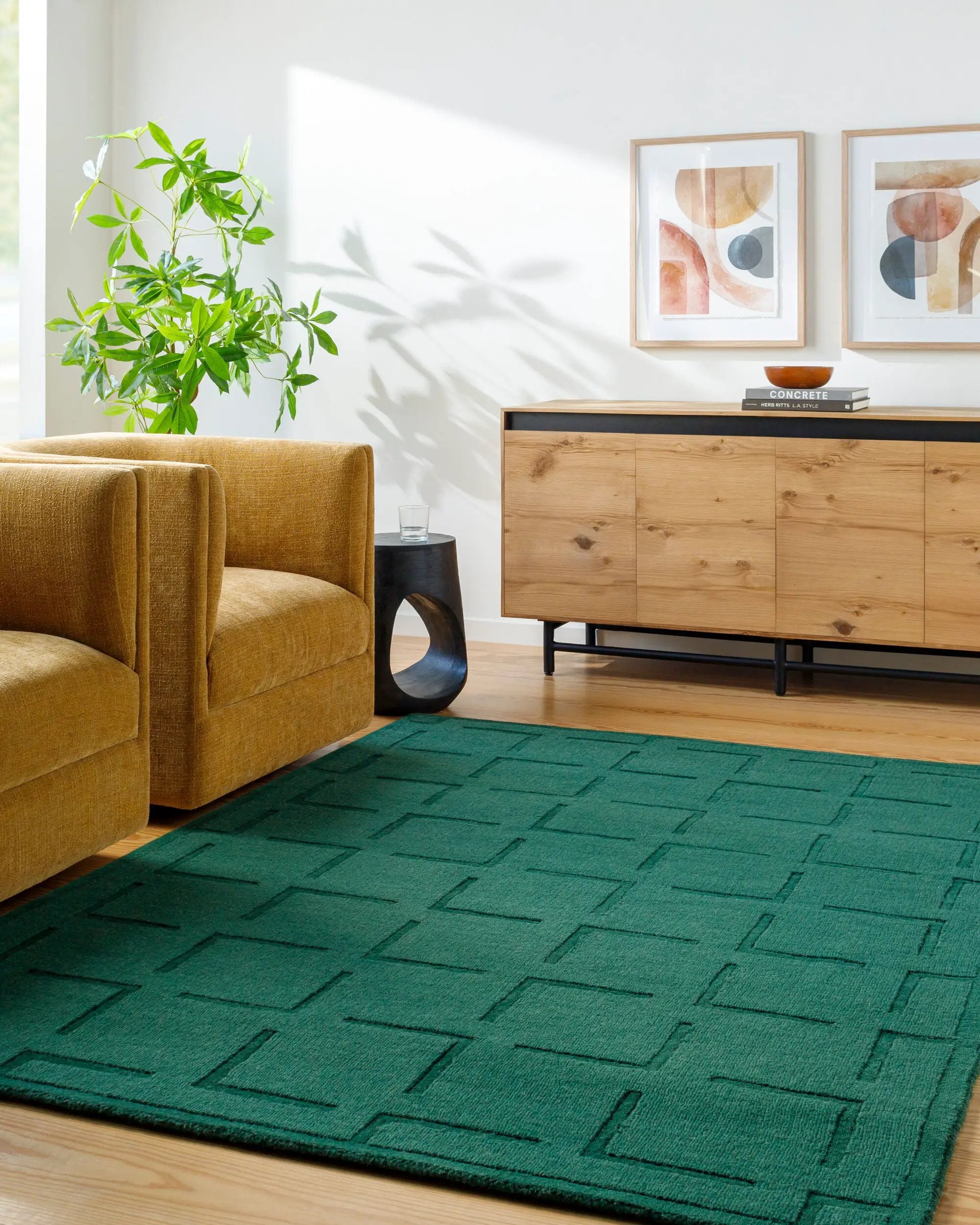 Livabliss Hand Loomed Mystique M-5490 Emerald Green wool rug with textured geometric weave pattern placed on hardwood floor beside mustard armchair and wooden sideboard.