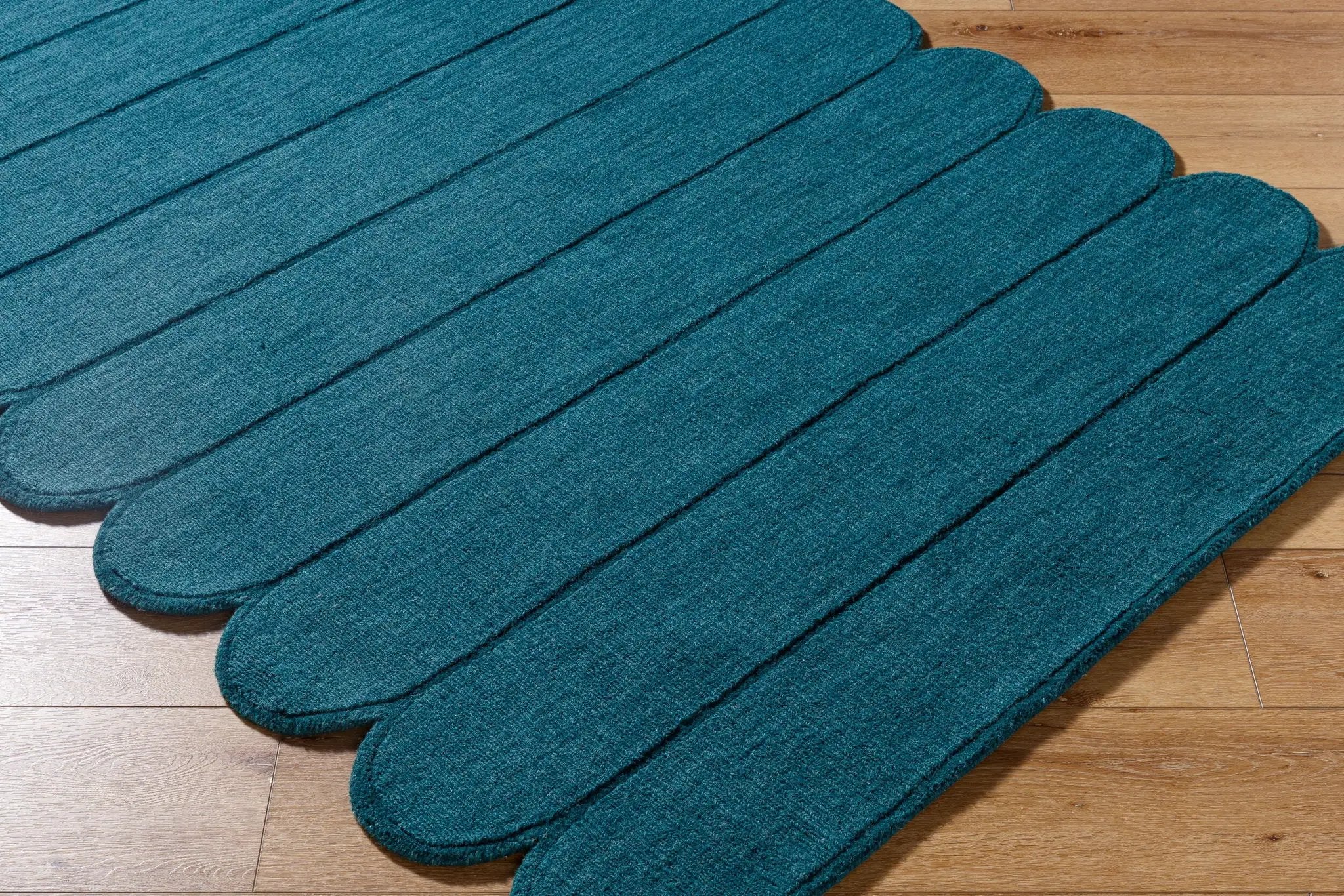 Livabliss Mystique M-5491 Teal hand-loomed wool area rug featuring distinct scalloped edge and soft medium-pile texture on hardwood flooring.