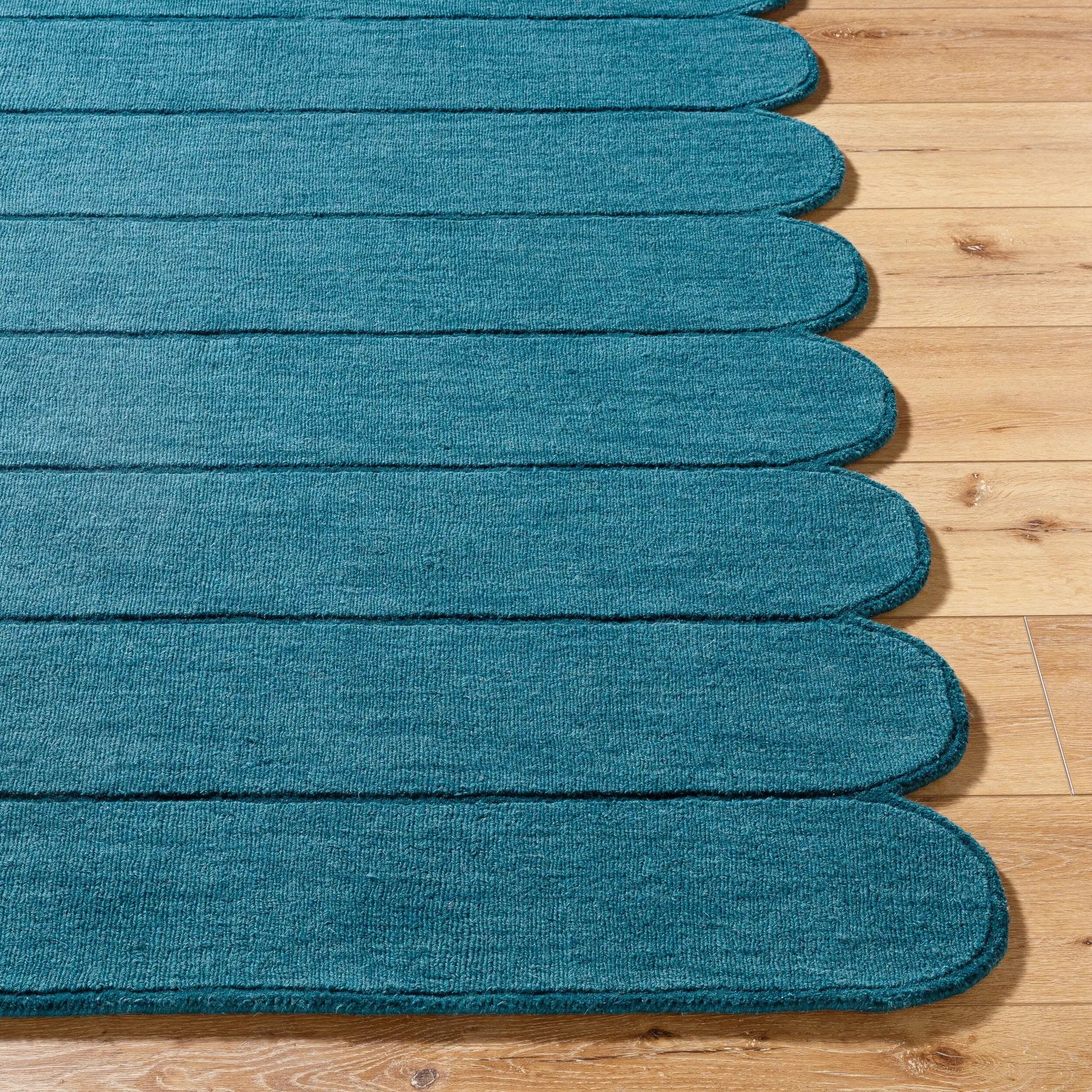 Livabliss Mystique M-5491 Teal hand-loomed wool area rug with distinctive scalloped edge and medium-pile texture on hardwood floor.