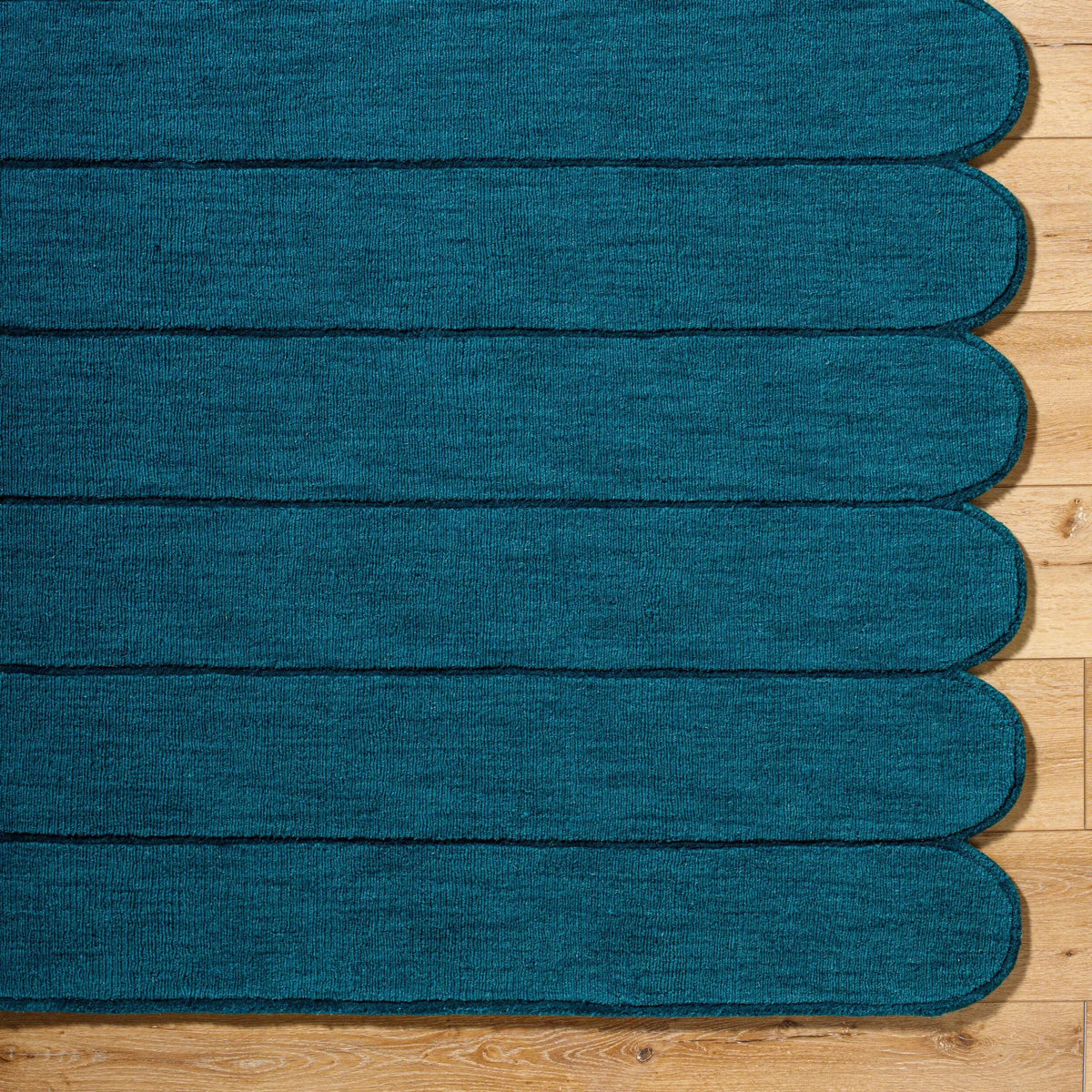 Livabliss Hand Loomed Mystique M-5491 Teal wool area rug with medium-pile texture and distinctive scalloped edge resting on hardwood flooring.