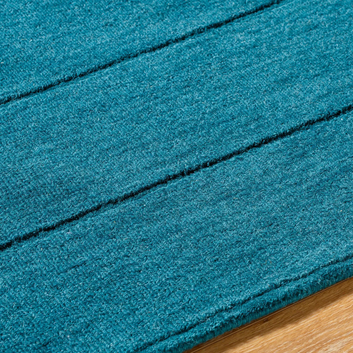 Livabliss Hand Loomed Mystique M-5491 Teal wool area rug with medium-pile texture and distinctive dark horizontal lines resting on hardwood flooring.