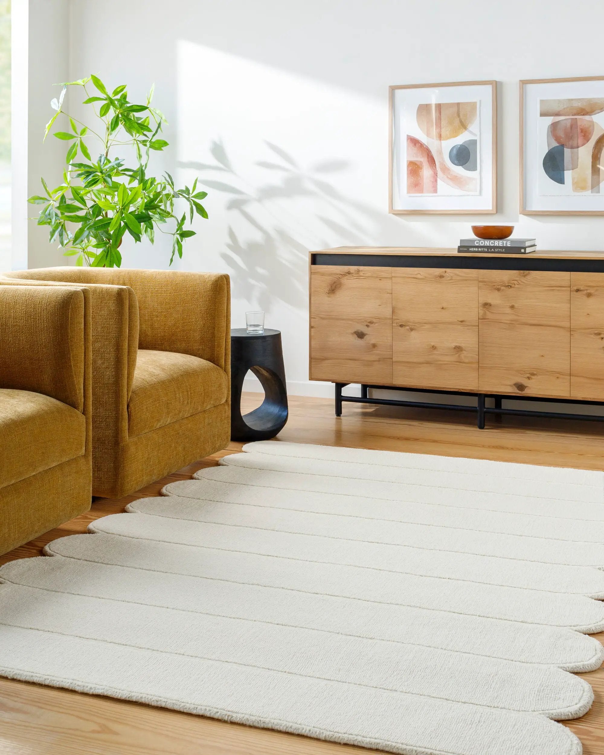 Livabliss Hand Loomed Mystique M-5492 Ivory area rug with unique scalloped edges and textured stripes lies on hardwood floors beside a mustard armchair and wooden sideboard in a sunlit living room.