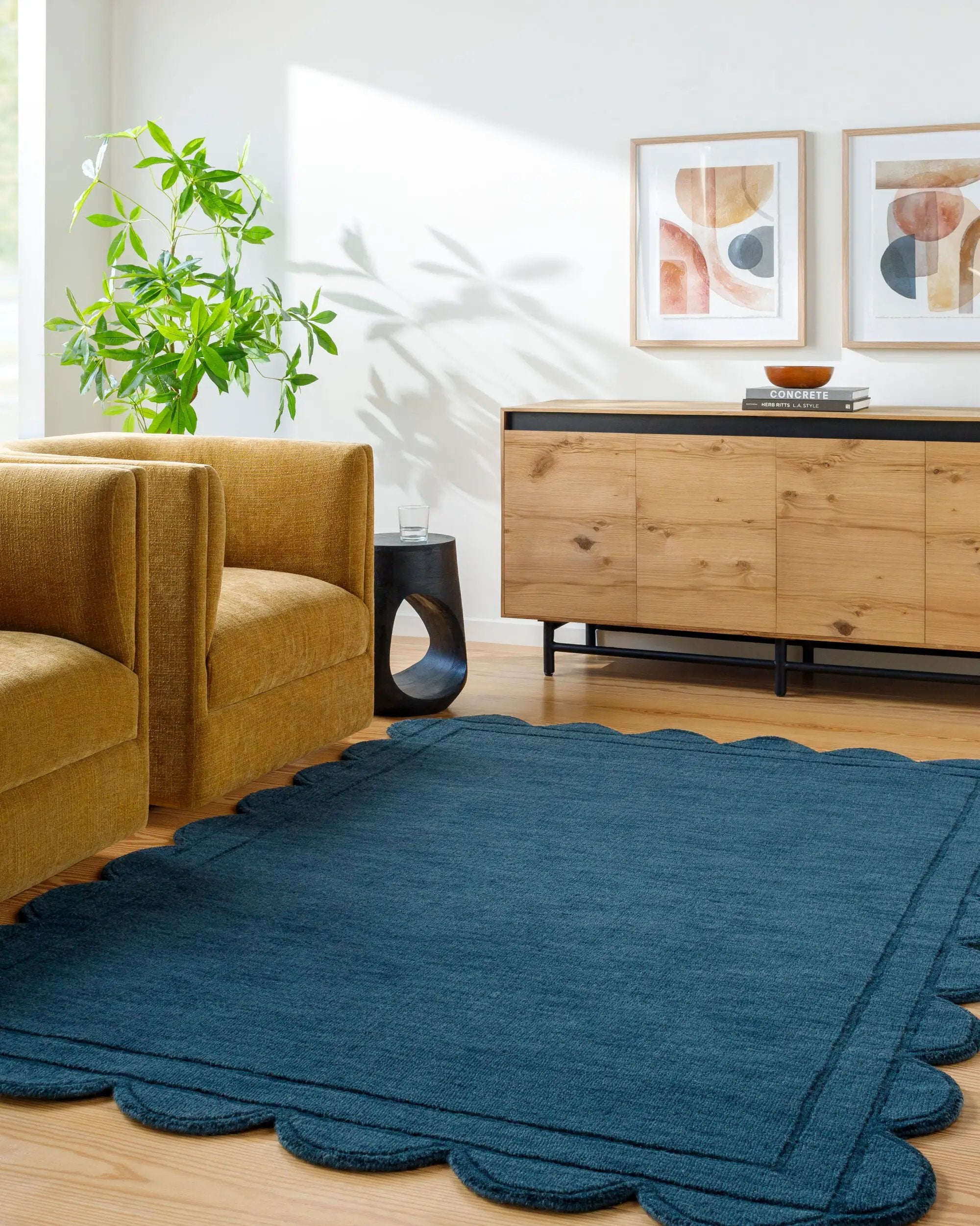 Hand loomed Livabliss Mystique M-5493 indigo wool area rug with scalloped edges adds texture to a modern living room featuring mustard seating and natural wood accents.