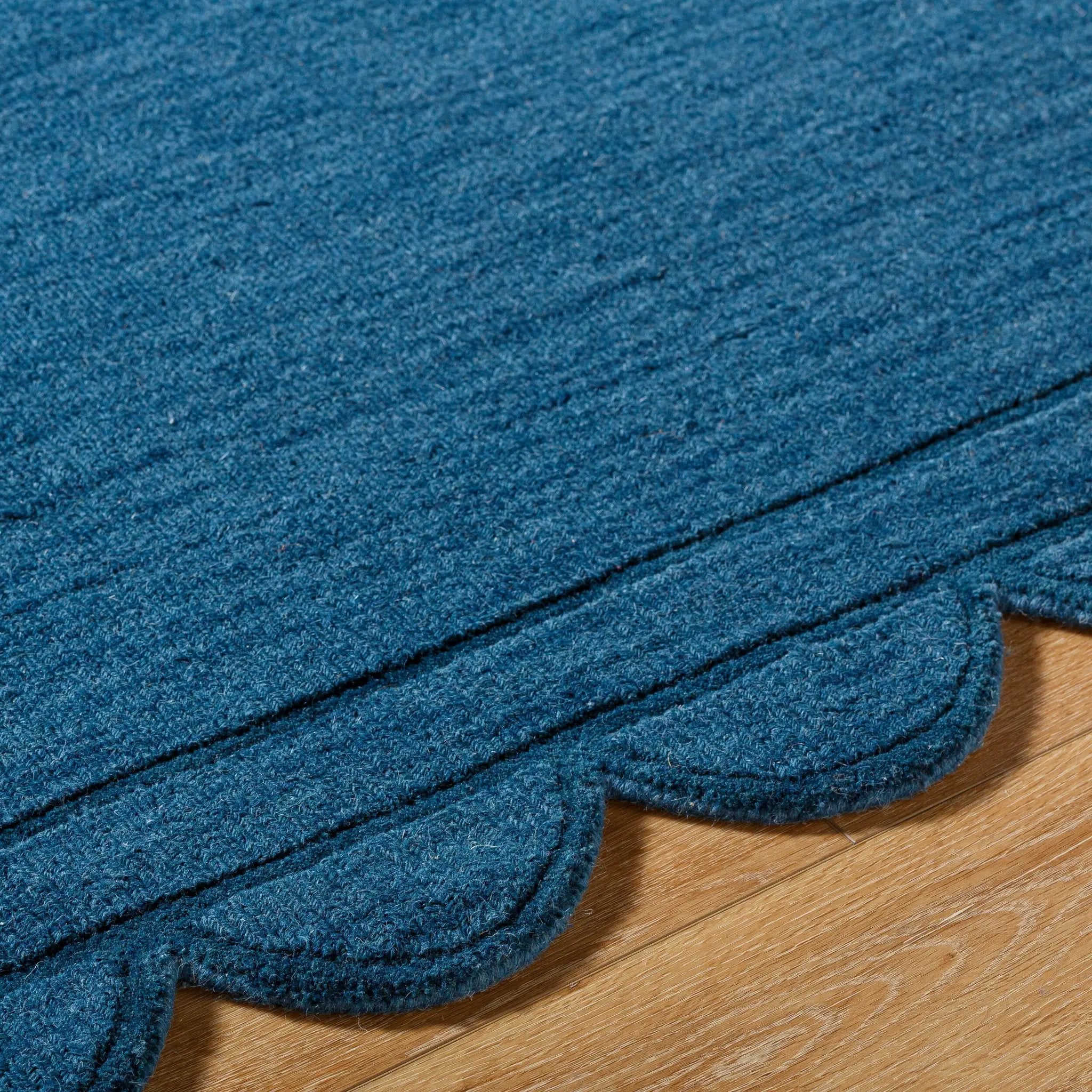 Livabliss Mystique M-5493 Indigo wool hand loomed area rug with scalloped edge and scalloped border resting on hardwood flooring.