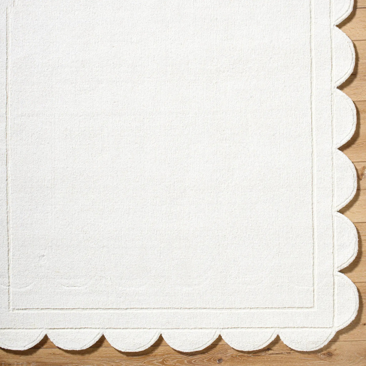 Livabliss Mystique M-5494 Ivory hand-loomed wool area rug featuring a distinct scalloped edge and subtle embossed border pattern on hardwood flooring.