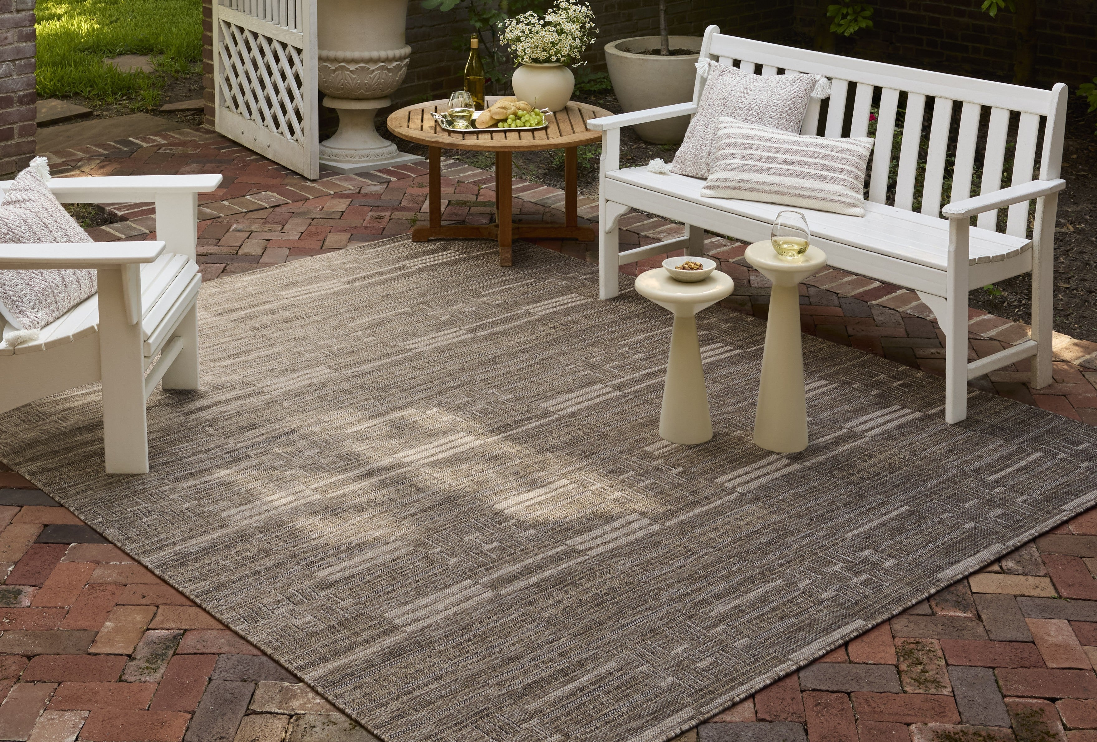 Loloi Birch Collection indoor/outdoor rug featuring an understated linear design on a brick patio with white wooden furniture.
