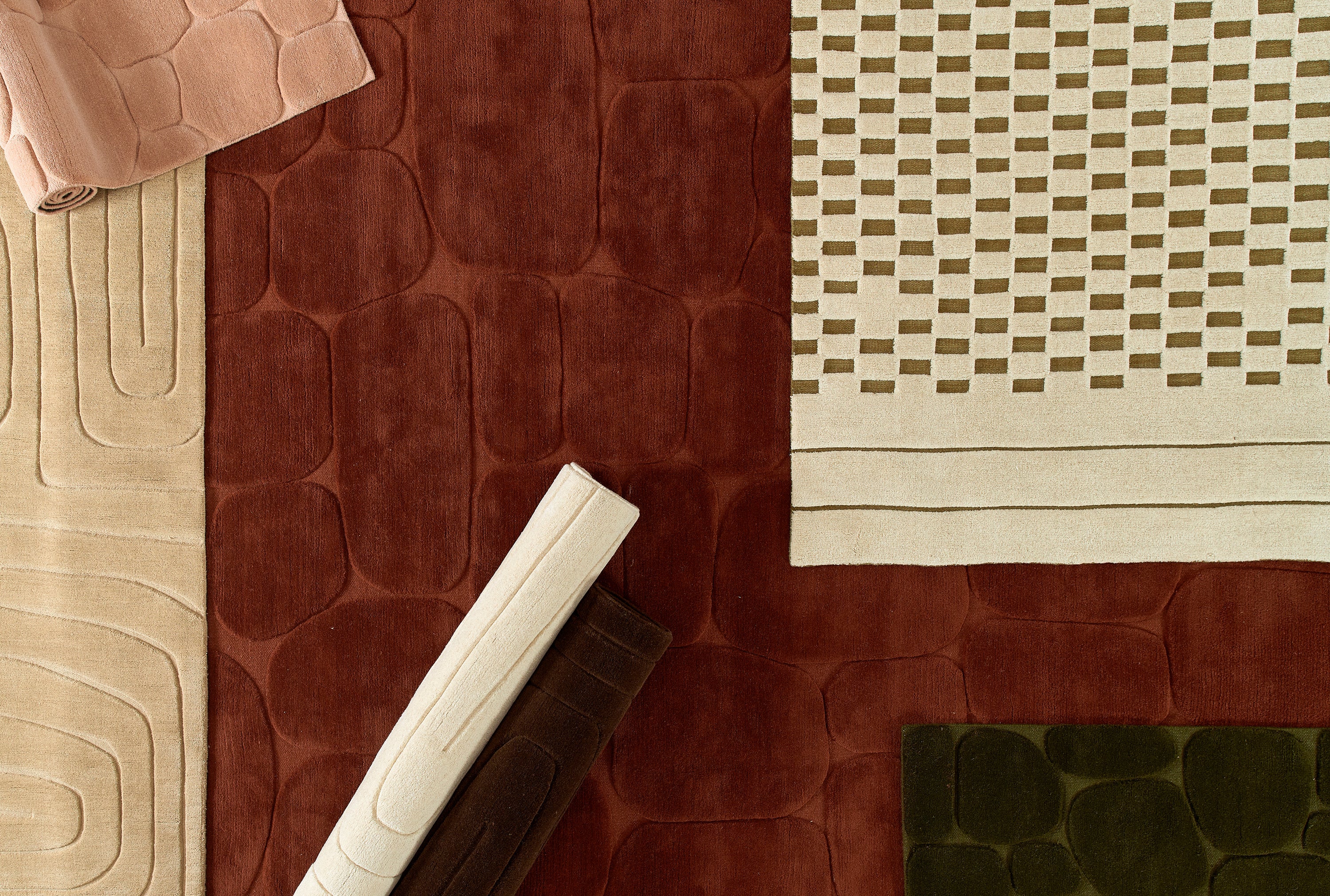 Hand-loomed Canyon area rug with sculpted high/low pile in moss green, rusted red, and warm neutrals, featuring organic, nature-inspired motifs.