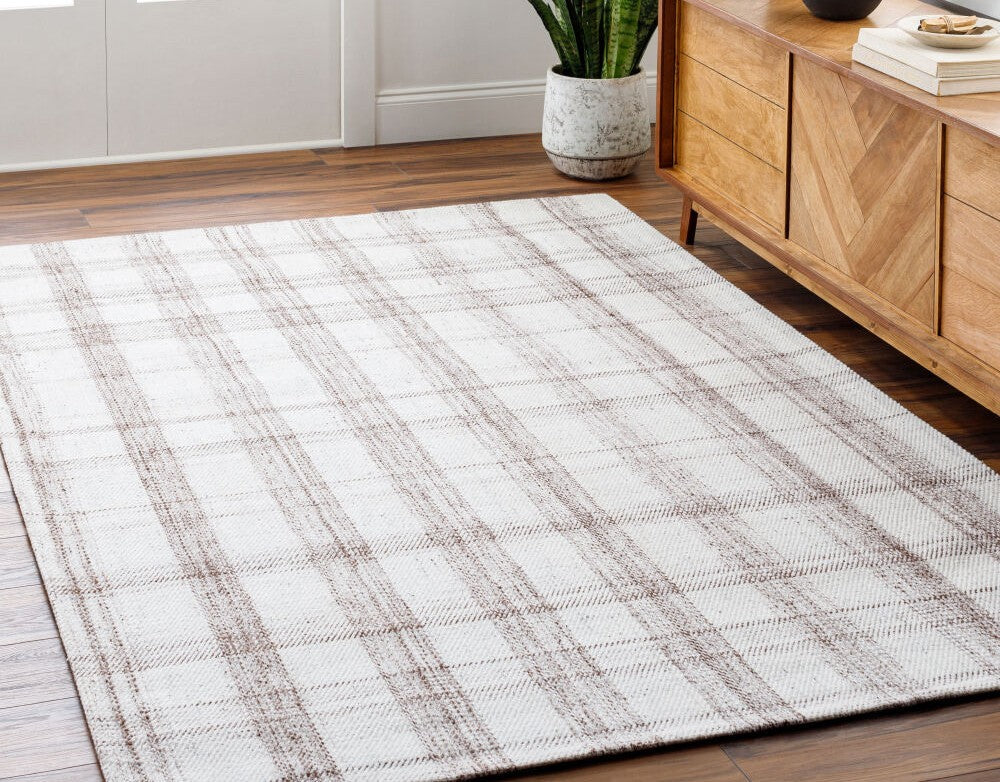 Becki Owens x Livabliss Sammy rug in cream and brown plaid, made from recycled PET yarn, displayed on hardwood floor beside wooden console.