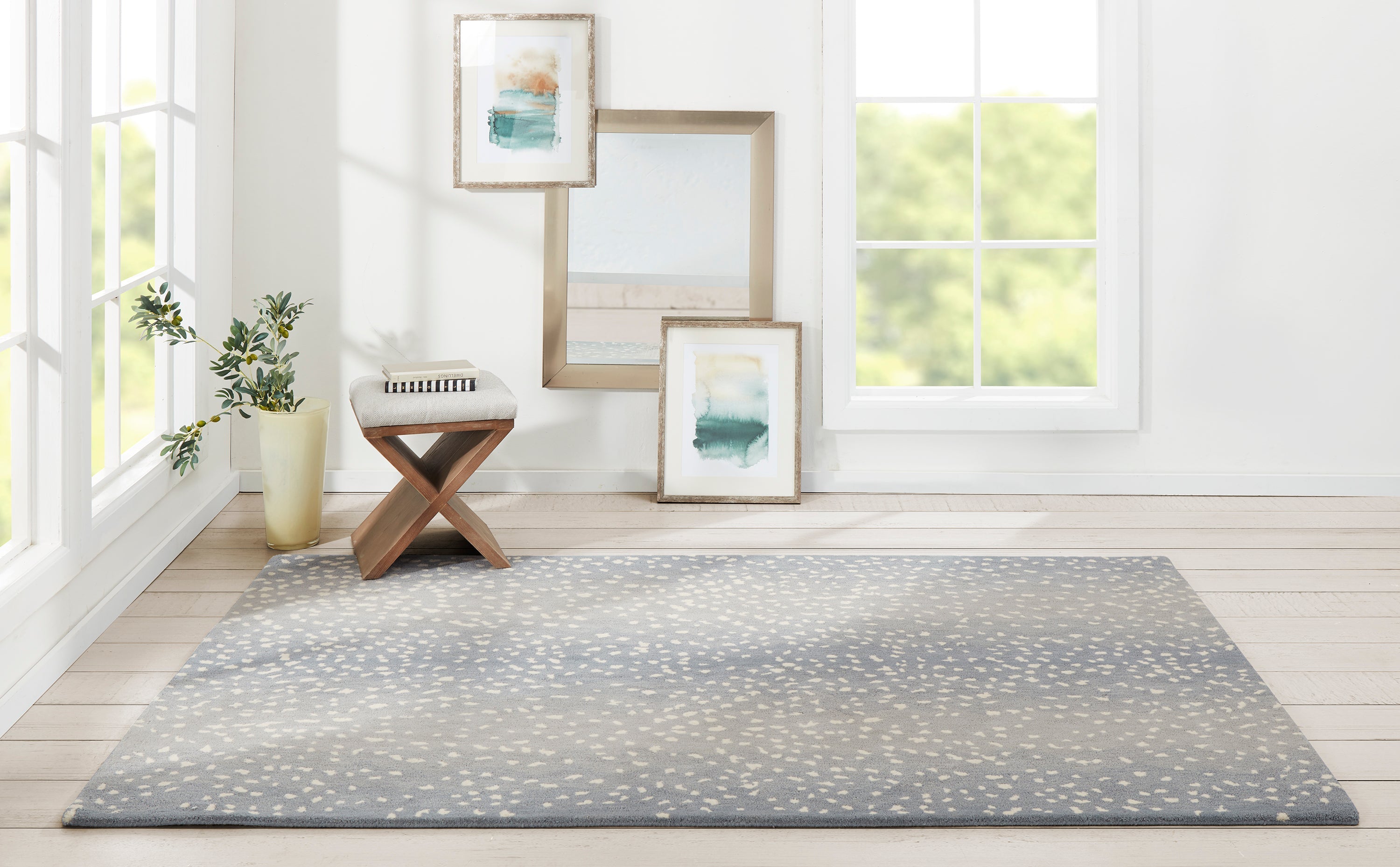 Erin Gates by Momeni Woodland Rug Collection in a bright room with a blue-gray dotted area rug, framed art, and greenery.