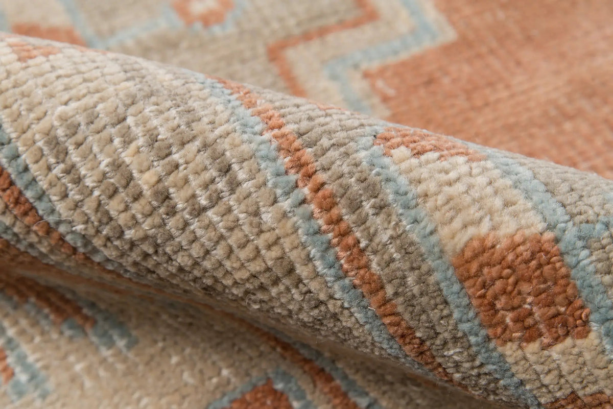 Rolled rust and blue Erin Gates by Momeni hand-knotted Concord CRD-1 Walden area rug featuring jagged tribal geometric patterns and textured Anatolian-inspired design.