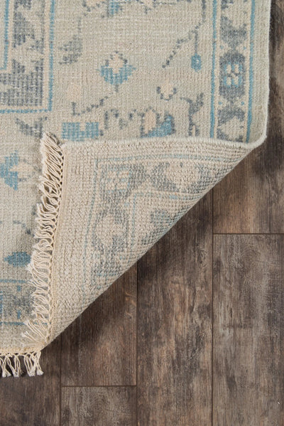 Erin Gates by Momeni Concord CRD-3 (Lowell) Ivory Area Rug corner lifted on wood floor, revealing textured weave, blue traditional patterns, and fringed edge.