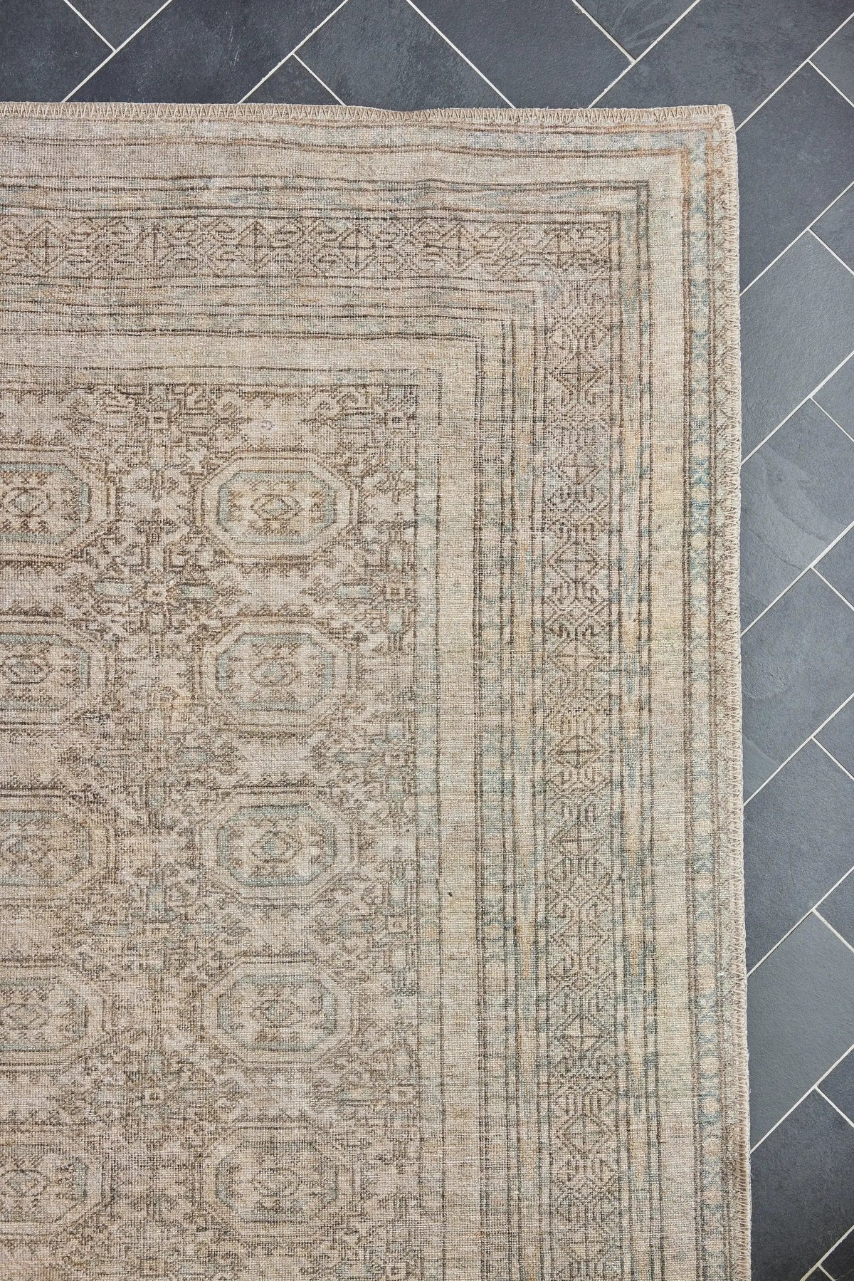 Erin Gates by Momeni Dorset DOR-1 Warren green area rug corner with vintage pattern and fringed edge on dark herringbone tile.
