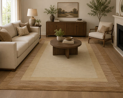 Loloi Hamilton HM-01 area rug in layered beige and tan tones is styled in a bright, modern living room with a cream sofa, round wooden coffee table, and wooden sideboard.