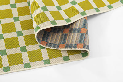 Icon ICN-1 Green Area Rug with lime-yellow checkered pattern and teal accents, partially rolled.