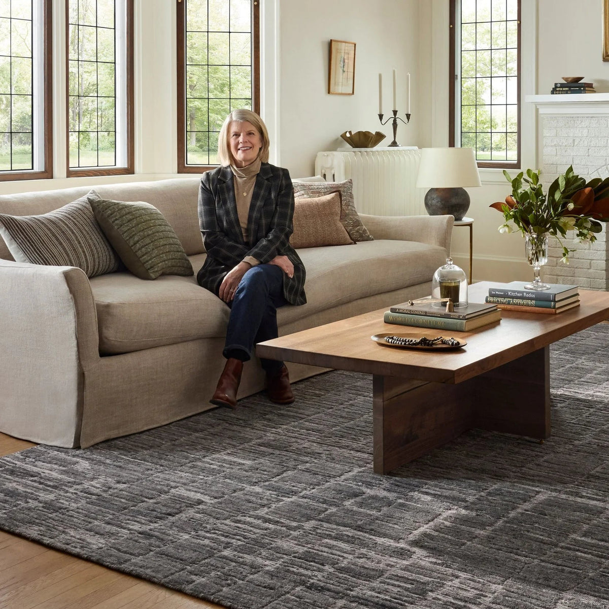 Jean Stoffer x Loloi-inspired living room featuring Daniel DAN-01 charcoal gray geometric area rug, neutral furnishings, warm wood accents, and a classic white brick fireplace for timeless, sophisticated style.