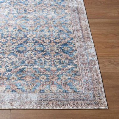 Amelia Slate Blue Area Rug with a distressed traditional pattern on a wood floor.