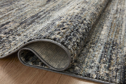 A power-loomed 100% polyester area rug featuring contemporary and abstract design and vibrant multi-toned and cool slate tones, the Soho SOH-06 Multi / Slate Area Rug adds character to any room