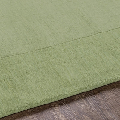 Livabliss Mystique M-310 medium green hand-loomed wool area rug with balanced high and low pile texture resting on dark wood flooring.