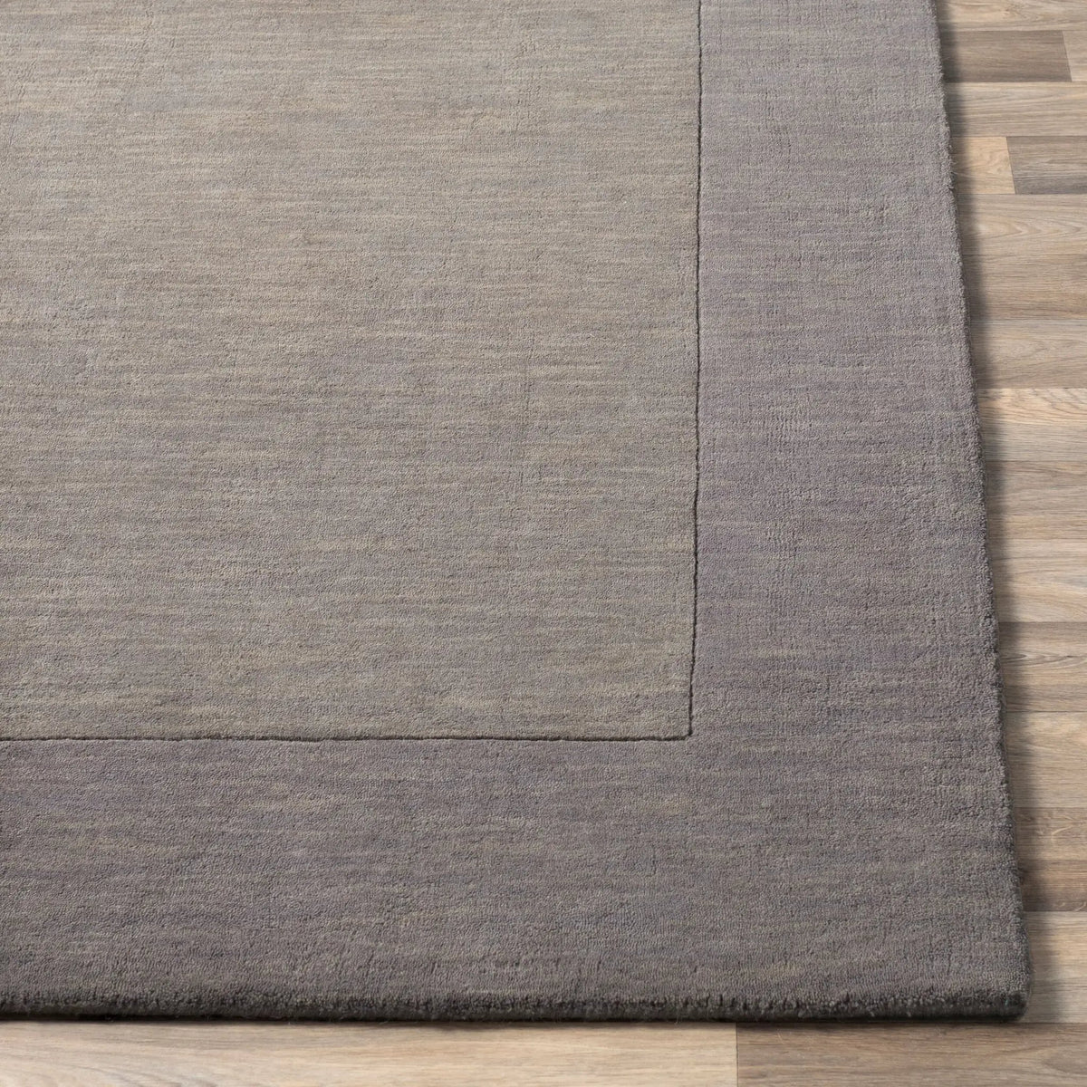 Livabliss Mystique M-312 charcoal area rug with high-low pile texture and defined border on wood flooring.