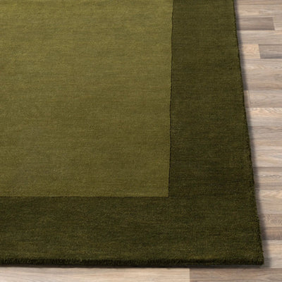 Livabliss Mystique M-315 Olive wool area rug with lighter center panel and dark border, featuring dynamic high-low pile texture on wood flooring.