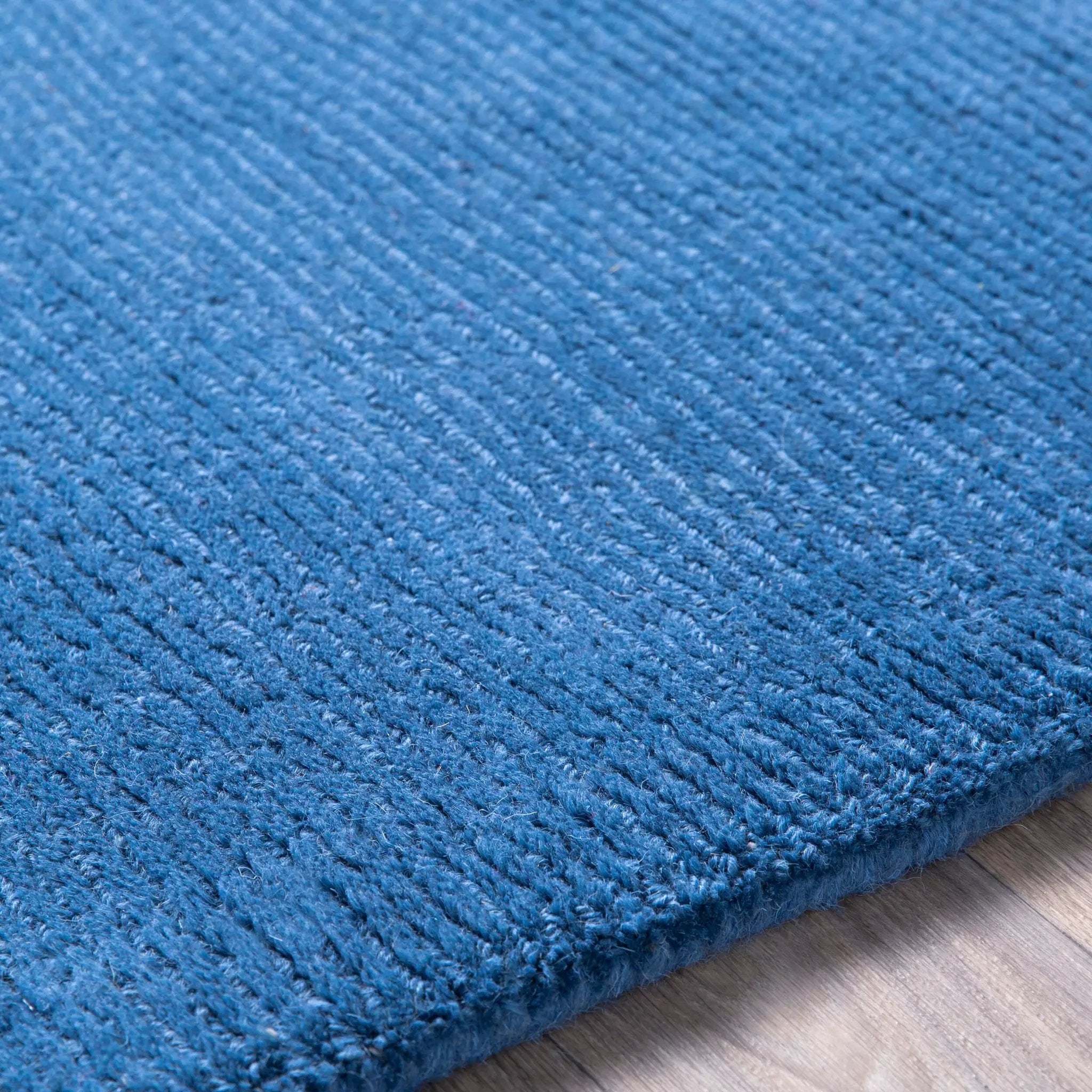 Close-up texture of a hand-loomed Livabliss Mystique M-330 dark blue wool area rug featuring a high-pile contemporary weave on wood flooring.