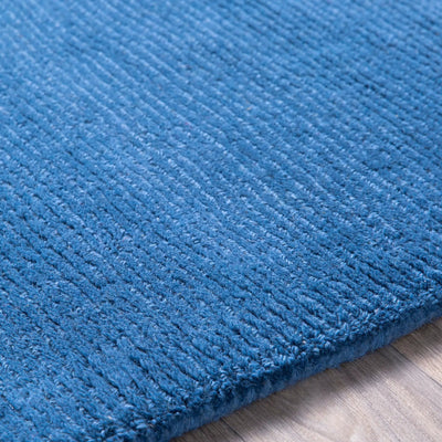 Close-up texture of a hand-loomed Livabliss Mystique M-330 dark blue wool area rug featuring a high-pile contemporary weave on wood flooring.
