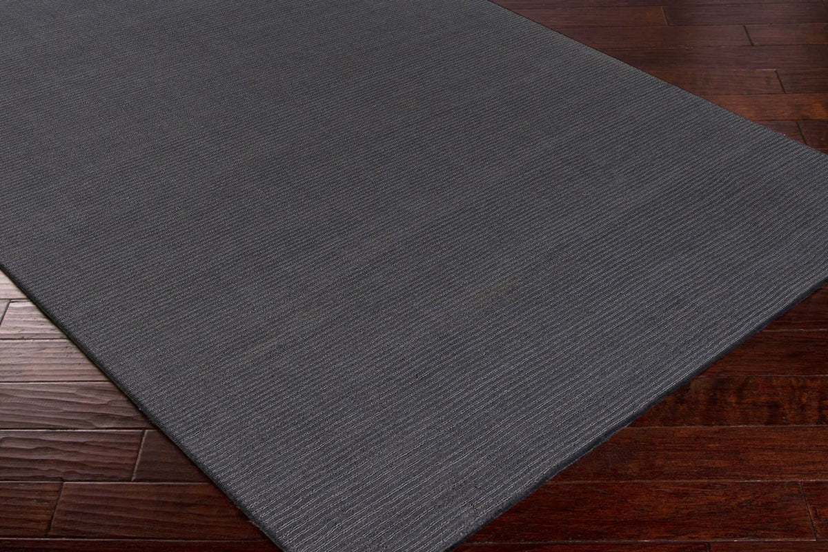 Livabliss Mystique M-341 Charcoal area rug with modern ribbed texture laying on dark hardwood flooring, featuring hand-loomed construction and refined artisanship.