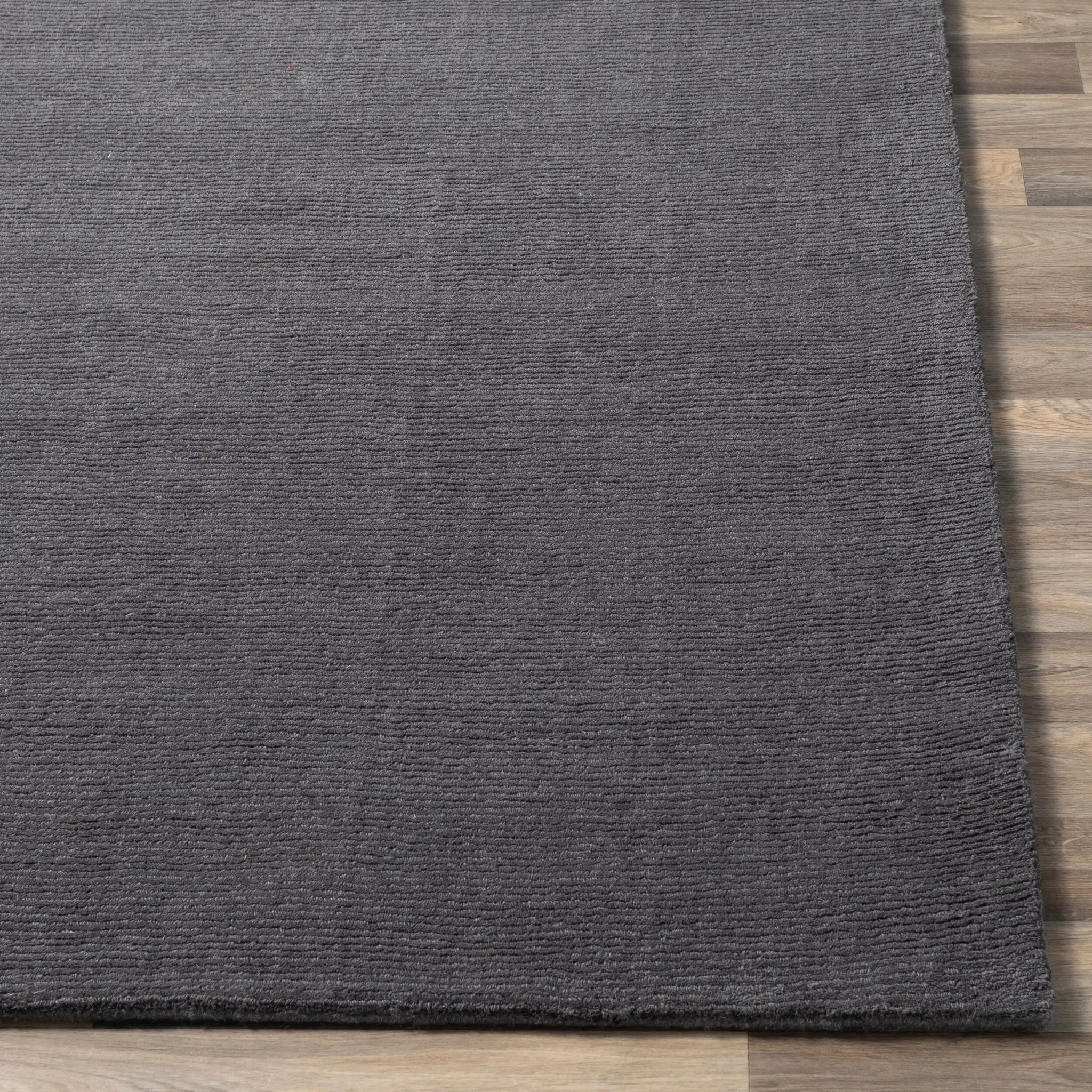 Livabliss Mystique M-341 Charcoal wool area rug with textured high-low pile surface laid on light wood flooring, showcasing hand-loomed craftsmanship.
