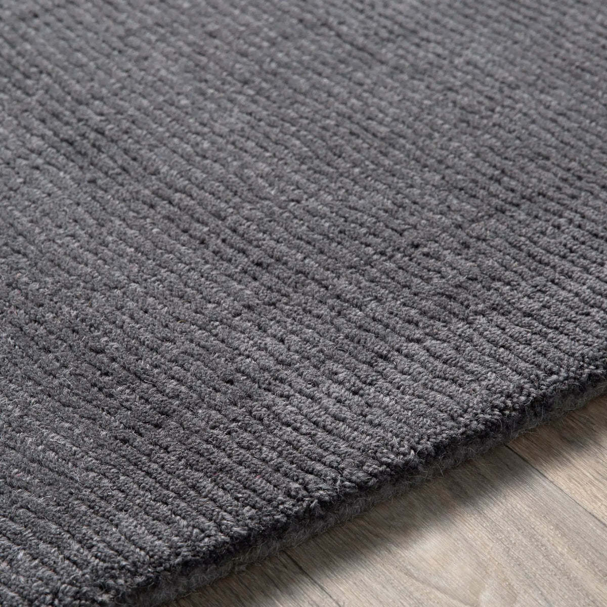 Livabliss Mystique M-341 Charcoal high-low pile wool area rug with hand-loomed texture and modern silhouette resting on wood flooring.