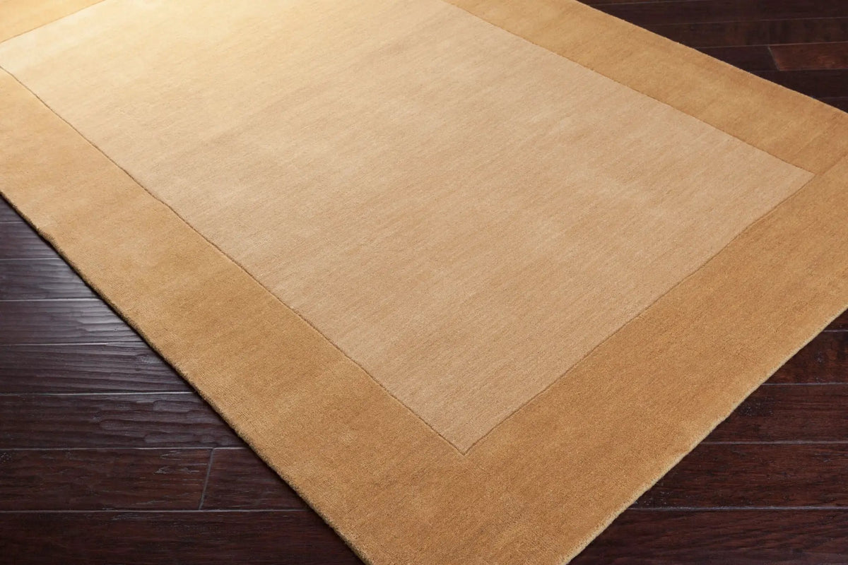 Textured Camel color Livabliss Mystique M-345 area rug with a darker border on dark wood flooring, featuring traditional hand-loomed comfort for modern interiors.