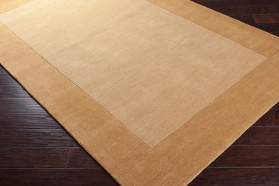 Textured Camel color Livabliss Mystique M-345 area rug with a darker border on dark wood flooring, featuring traditional hand-loomed comfort for modern interiors.