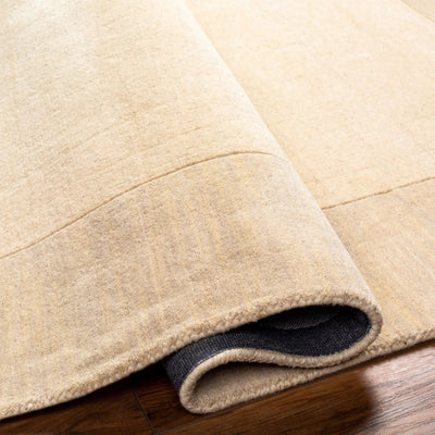 Livabliss Mystique M-348 Cream hand-loomed Indian wool area rug with high-low pile texture, corner rolled to show dark backing on wood floor.