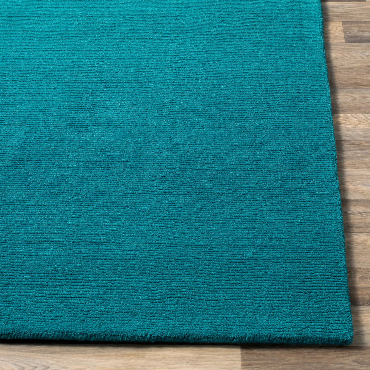 Livabliss Mystique M-5330 Deep teal hand-loomed wool area rug with contemporary high-low texture resting on light wood flooring.