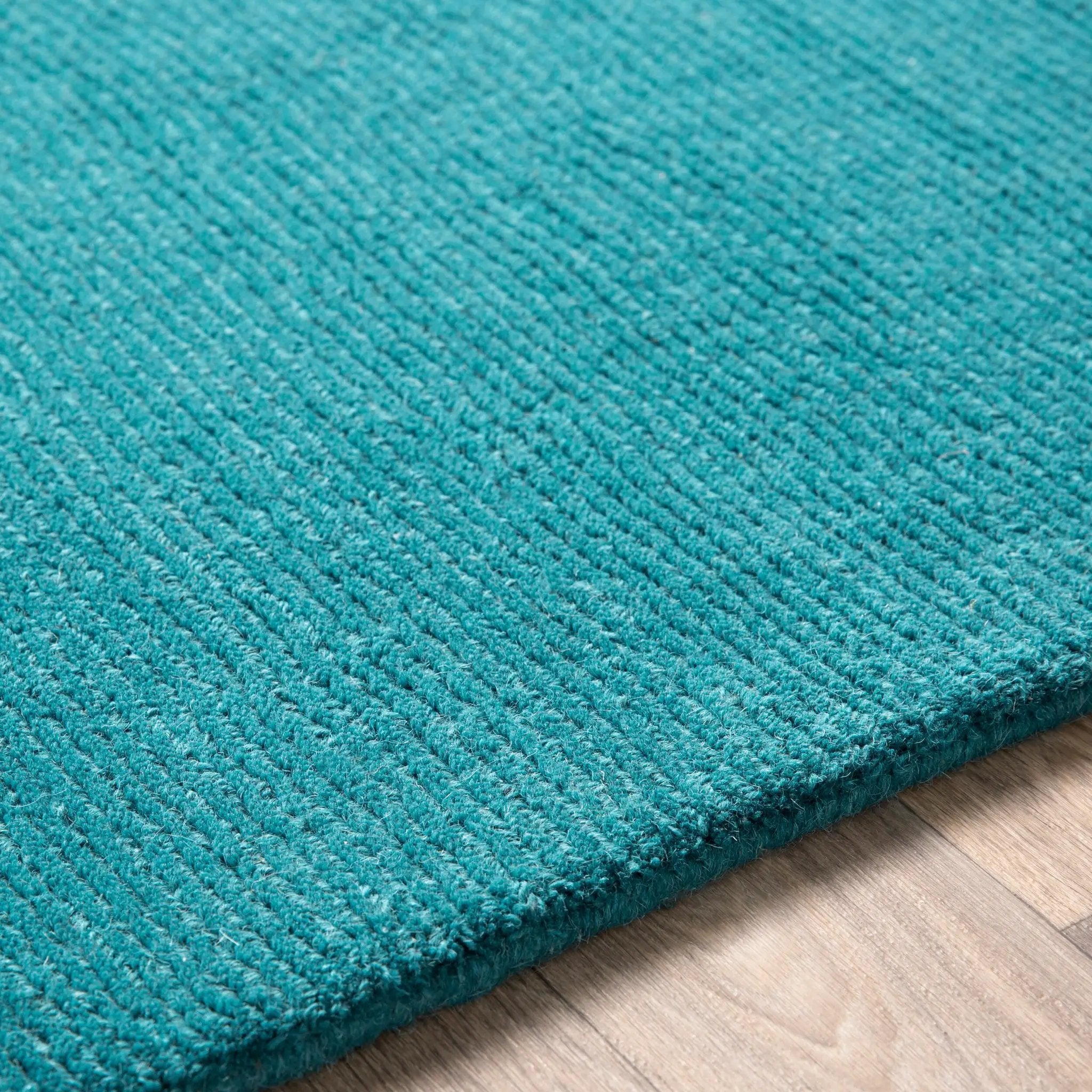Livabliss Mystique M-5330 Deep teal hand-loomed wool area rug featuring a durable contemporary high-low texture resting on light wood flooring.