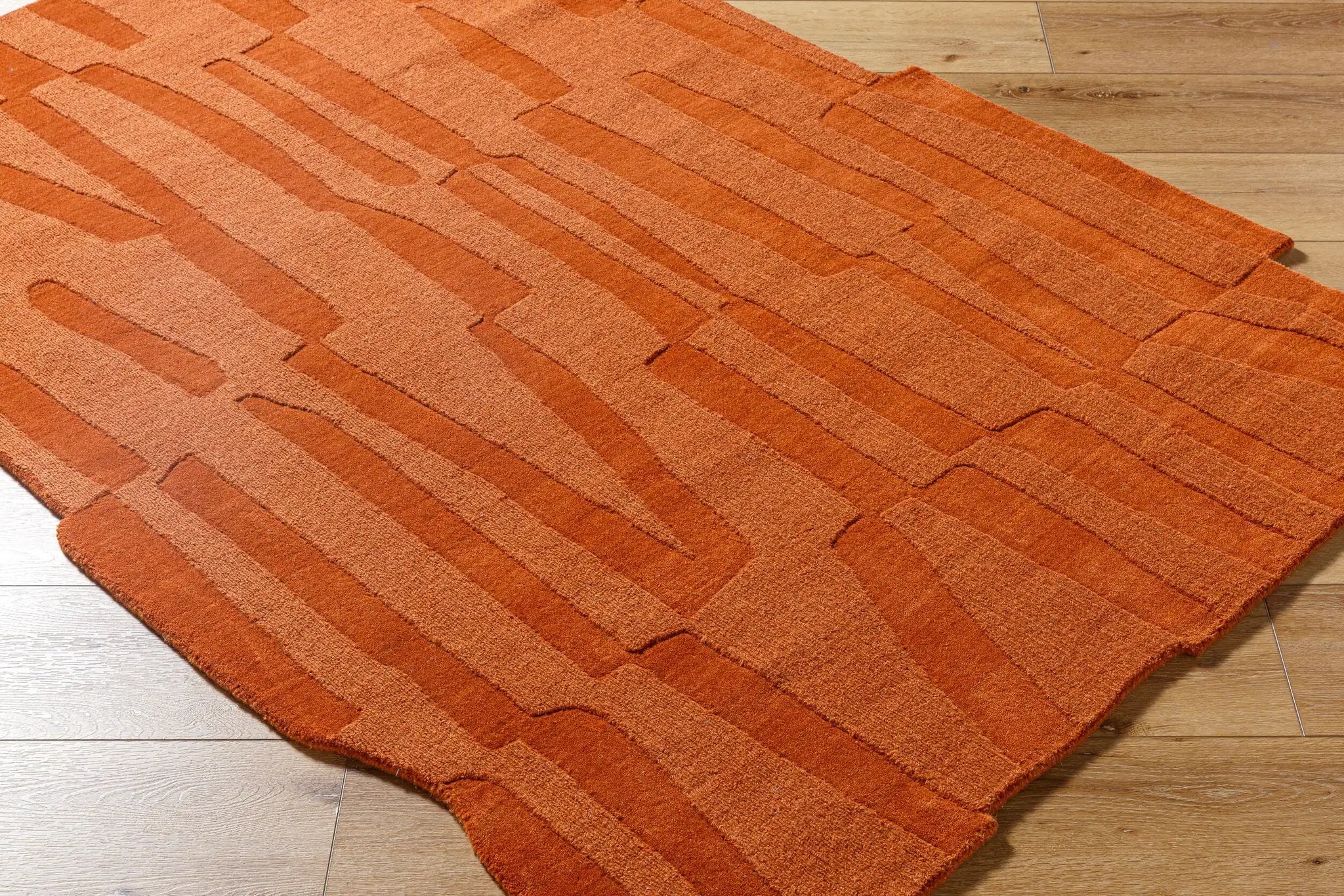 Hand-loomed Livabliss Mystique M-5488 burnt sienna wool area rug featuring artisan craftsmanship, medium pile texture, and abstract linear patterns on wood flooring.